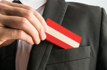 A man picks up a business card that looks like the flag of Austria